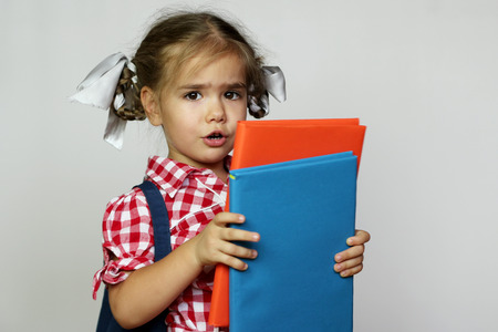 Portrait of cute smiling girl with backpack and colorful books, education and back to school conceptの写真素材