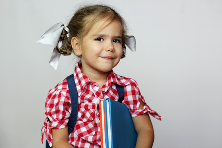 Portrait of cute smiling girl with backpack and colorful books, education and back to school conceptの写真素材