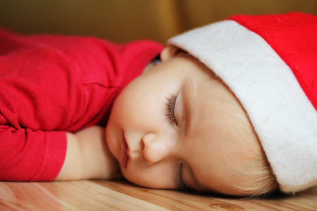 Cute toddler boy with Santa hat sleeping on the floor, Christmas indoorの写真素材