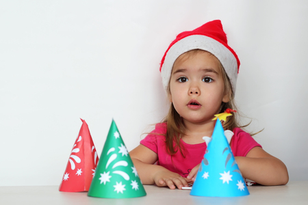Surprised pretty girl looking out near handmade New Year trees on white background, indoor portraitの写真素材