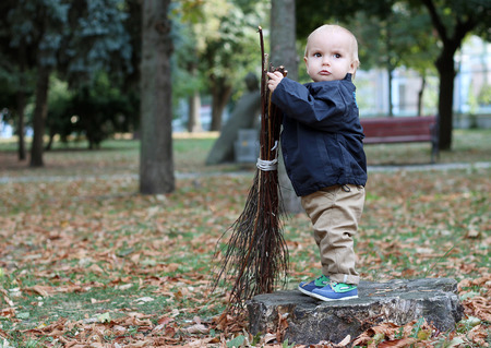 Cute baby boy holding a broom in the city parkの写真素材