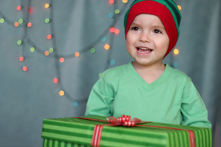 Portrait of happy little boy opening gift in the box over Christmas background, winter holiday family conceptの写真素材