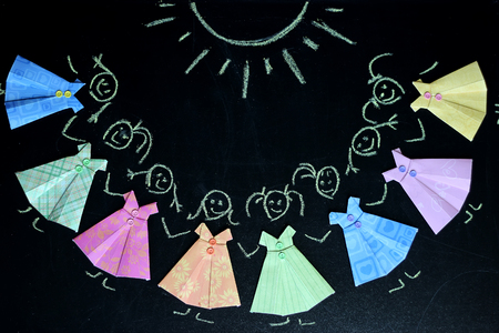 Little girls drawn with chalk and wearing in colorful paper dresses lying on the blackboard, selective focus, creativity and art concept, beauty and fashionの写真素材