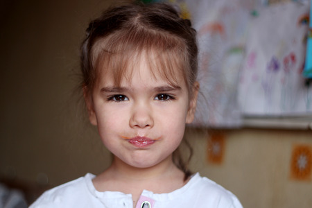 Happy gorgeous little girl with red mustache and mouth full with vegetable juice looking at camera in the kitchen at home, food and drink concept, healthy food, indoor closeupの写真素材