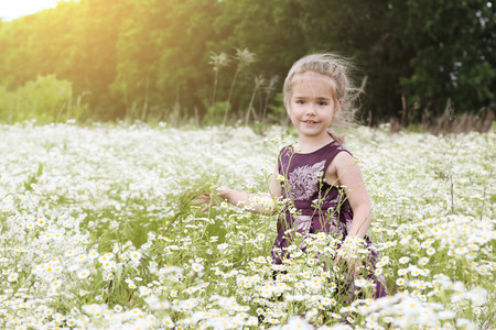 Cute little girl wearing beautiful dress dancing among chamomile field, beauty and fashion, happy childhood, summer vacation, outdoorの写真素材