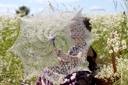 Cute little girl looking through the openwork sun parasol while she walking among the chamomile field in summer, shabby chic charm, country style concept, beauty and fashion, summer outdoorの写真素材
