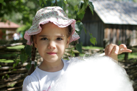 Adorable girl eating cotton candy at amusement park, summer vacation holidays, happy summertime concept の写真素材