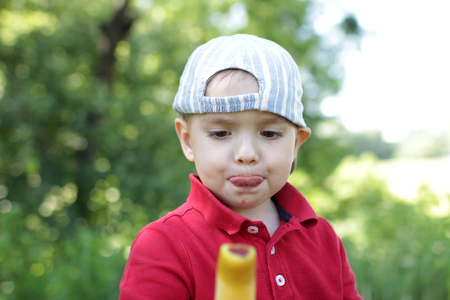 Close-up portrait of toddler boy dirty after eating an ice-cream, summer outdoor, happy family weekendの写真素材