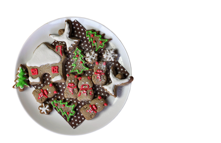 Festive Christmas plate with sweet cookies, house, snowflakes and pigs, new year symbol over white background, classical red and brown Christmas color, winter holidays concept, greeting card formatの写真素材
