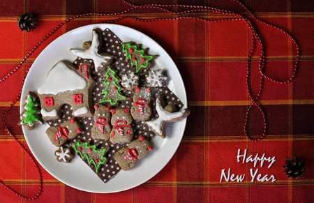 Festive Christmas plate with sweet cookies, house, snowflakes and pigs, new year symbol, classical red and brown Christmas color, winter holidays concept, greeting card formatの写真素材