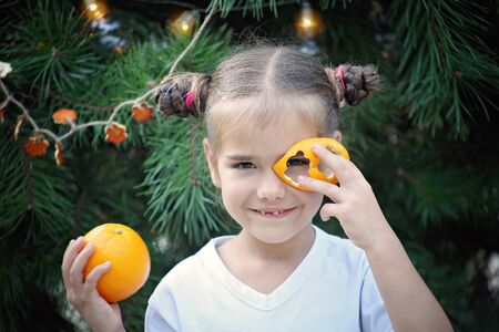 Cute school girl holding crafted Christmas garland made from the skin of oranges, zero waste lifestyle, reuse and ecological decorationの写真素材