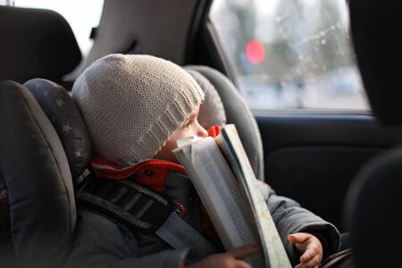 Adorable little boy exploring a map during his road trip on vacations with his parents. Happy family...