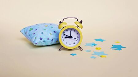 Yellow alarm clock and light blue pillow, healthcare and healthy lifestyle, active morning, conceptの写真素材