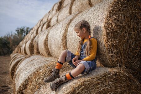 Happy cute 7-8 years old girl in trendy jeans overall and orange colors t-shirt and socks having fun...