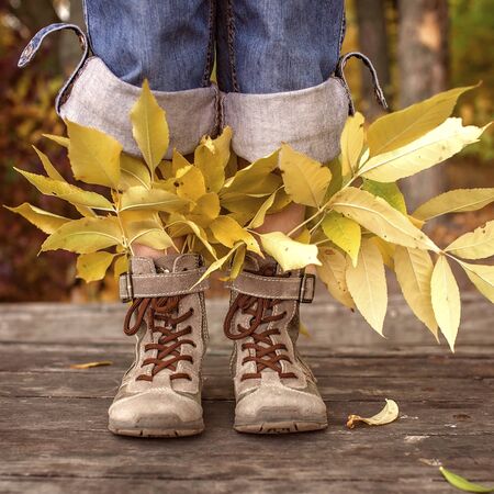 Happy cute 7-8 years girl in hipster style shoes with bright autumn leaves inside, trendy and stylish concept, inspirational lifestyleの写真素材