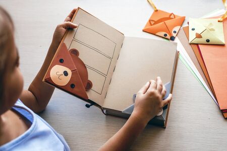 Smart cute kid girl holding a book with crafted paper corner bookmark, creative ideas for kids, fun...