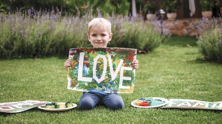 Cute toddler with darling hand print project kept his busy at home or outside at summer, drawing posters created with tape and fingers, easy and funny DIY with kids, early art education conceptの写真素材