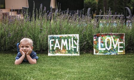 Cute toddler with darling hand print project kept his busy at home or outside at summer, drawing posters created with tape and fingers, easy and funny DIY with kids, early art education conceptの写真素材