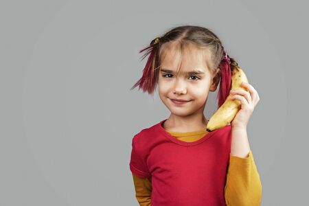 Freakish kid with pinky hair in eyeglasses holds misshapen wrong color fruits and vegetables, giants, with tiny spots and scars, isolated over white background, people and waste food trend conceptの写真素材