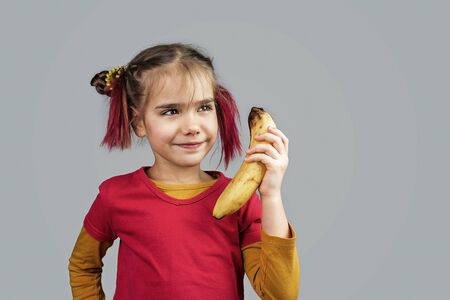 Freakish kid with pinky hair in eyeglasses holds misshapen wrong color fruits and vegetables, giants, with tiny spots and scars, isolated over white background, people and waste food trend conceptの写真素材