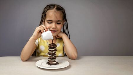 Stylish school girl pouring liquid hot chocolate on a pile of different chocolate pieces, there is never much chocolate, healthy food concept, studio shot, meme for world chocolate dayの写真素材