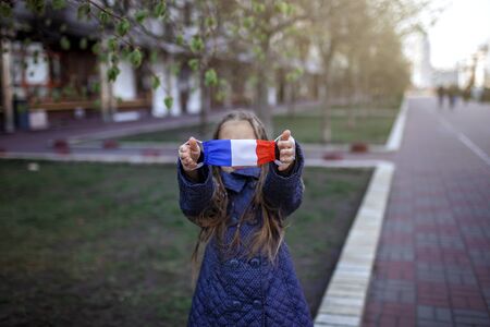 Happy little girl wearing off the respirator medical mask in national France colors because of the end of quarantine in the country, happiness and hope, stop virus spreading, outdoor lifestyleの写真素材