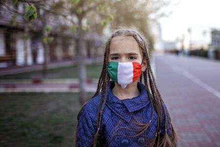 Happy little girl wearing off the respirator medical mask in national Italy colors because of the end of quarantine in the country, happiness and hope, stop virus spreading, outdoor lifestyleの写真素材