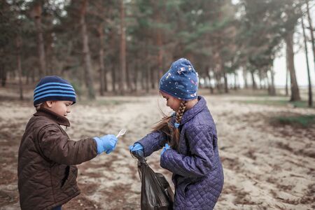 Young volunteers, brother and sister with their father, cleaning area in forest near beach and gathering trash in bag, save the planet concept, ecology problemの写真素材