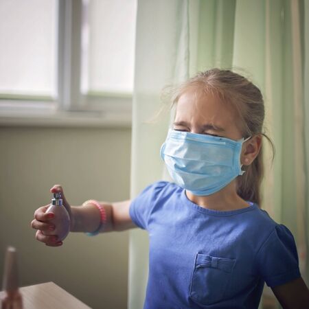 Beauty and fashion in new normal life, pretty girl playing in beauty salon holding a perfume bottle and applying it, she is wearing in medical respirators, safety and health careの写真素材