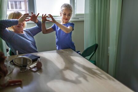 Multigenerational relations, grandmother playing in beauty salon and helping grandkid to do makeup, they are happy together, indoor family lifestyleの写真素材