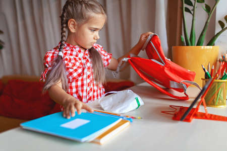 Back to school, new normal education. Cute girl in school uniform greeting somebody via video call...