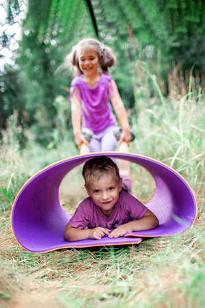 Active healthy weekend. Happy kids, boy and girl, having rest and fun on the purple yoga mat during their hiking in the forest, local travel. Staycation in new normal life. Summer outdoor lifestyleの写真素材