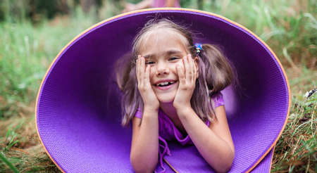 Active healthy weekend. Happy kid having rest and fun on the purple yoga mat during their hiking in the forest, local travel. Staycation in new normal life. Summer outdoor lifestyleの写真素材