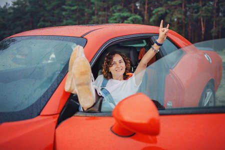 Autumn road trip, freedom and solo traveler. Pretty woman sitting in the car on the bank of sea,...