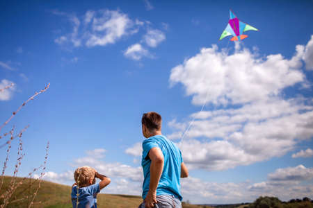 Happy childhood and summertime. Young boy with father having fun and playing with a kite on the meadow, blue sky and beautiful landscape. Summer outdoor, cope space backgroundの写真素材