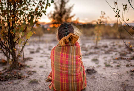 Family autumn walking. Cute girl in orange coat wrapping up in soft plaid among golden forest at fall. Warm weather and warm stories, outdoor lifestyleの写真素材