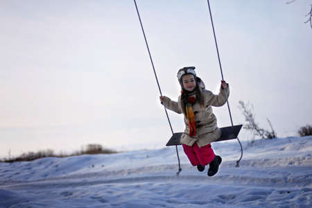 Smiling preschool girl in funny hat and warm coat decorating a pine tree with crafted toy among winter forest, walk outdoors, winter family lifestyle, zero waste Christmas celebrationの写真素材