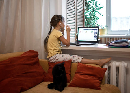 Distant education, online class meeting. Pretty schoolgirl in formal shirt but in pajama trousers...