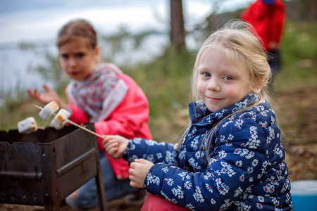 New normal escape step, wild nature walking and family outdoor recreation. Kids standing by the fire and cooking marshmallows, hike at weekend, lifestyleの写真素材