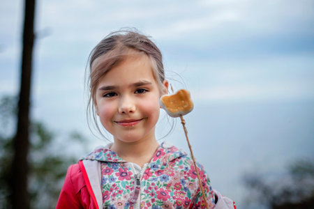 New normal escape step, wild nature walking and family outdoor recreation. Kids cooking and tasting marshmallows fried on fire, hike at weekend, lifestyleの写真素材