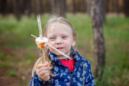 New normal escape step, wild nature walking and family outdoor recreation. Kids cooking and tasting marshmallows fried on fire, hike at weekend, lifestyleの写真素材