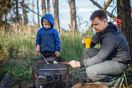 New normal escape step, wild nature walking and family outdoor recreation. Kids cooking and tasting marshmallows fried on fire, hike at weekend, lifestyleの写真素材