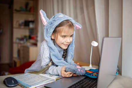 Distant education, online class meeting. Pretty schoolgirl wearing funny rabbit hat with ears to...
