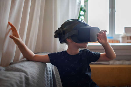 Cute girl wearing virtual reality at home, remote education experiment, future today, new online education, indoor lifestyleの写真素材