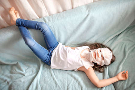 Teenage beautiful girl with long hair applying facial cosmetic mask and doing spa procedure at home, wellness, relaxation and beauty, indoor lifestyle, beauty salon at homeの写真素材