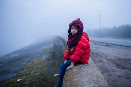 Girl walking alone along road in spring foggy day, uncertainty and hope concept, lifestyle outdoor....