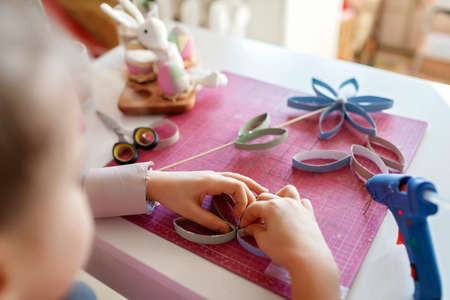 Cute girl doing flowers with toilet roll tube for Easter and Mother Day via online master class, zero waste crafts for kids, school and kindergarten, creative idea for holidays from internetの写真素材