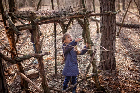 Young adventurers, boy and girl, building a wooden habitat in the wild forest during their social distant walking in lockdown time, walking on fresh air, outdoor active lifestyleの写真素材