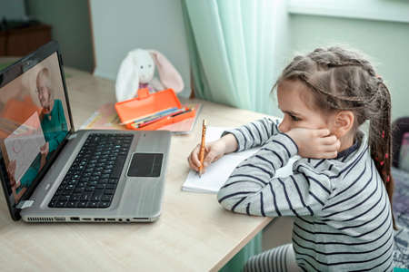 Pretty stylish schoolgirl studying homework math during her online lesson at home, social distance during quarantine, self-isolation, online education concept, home schoolerの写真素材