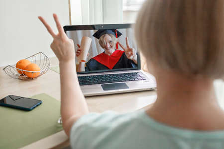 Virtual graduation and convocation ceremony. Senior woman congratulating her daughter in graduation...